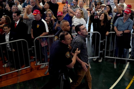 Two police officers march a protester out past the crowd gathered for Trump’s speech