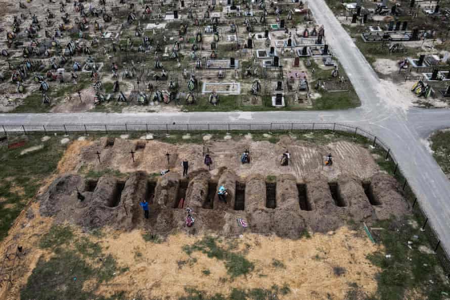 An aerial picture taken on 18 April 18 shows coffins being buried during a funeral ceremony at a cemetery in Bucha.