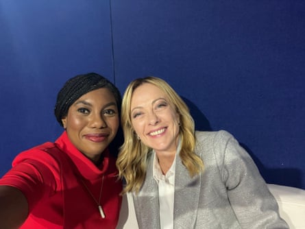 Kemi Badenoch and Giorgia Meloni smiling in a selfie. Badenoch wears a red jacket with a zip front and Meloni wears a glittery silver-grey jacket over a white blouse.