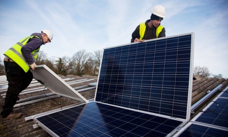 Fitters install solar panels on a barn roof at Grange farm, near Balcombe in west Sussex, England. 