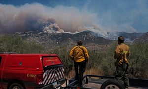 Firefighters look on as the Big Horn fire burns the Santa Catalina Mountains near Tucson.