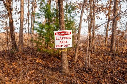 A sign that says danger blasting area keep out is affixed to a tree