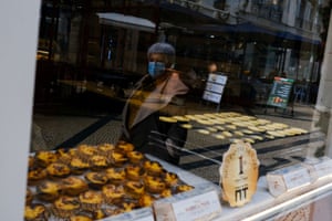 A woman wearing a protective mask passes by a bakery, as the government announced new coronavirus restrictions, in Lisbon, Portugal, on 21 December, 2021.