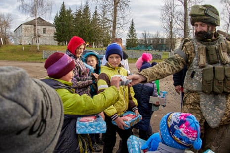 Ukrainian military members hand sweets and toys to children in Kupiansk.