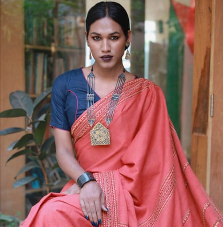 Portrait of a trans woman wearing a coral-coloured sari and elaborate necklace
