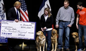 Donald Trump presents a mock check representing $100,000 to members of the Puppy Jake Foundation in Davenport, Iowa, on 30 January 2016.