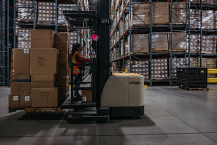 Woman driving a forklift with boxes in a warehouse
