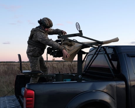 Soldier in the back of a truck with a large weapon used for shooting down aerial threats attached to the vehicle