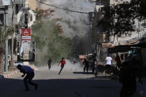 Palestinians rush for cover as debris flies around them after an Israeli strike on the Bureij camp for Palestinian refugees in central Gaza