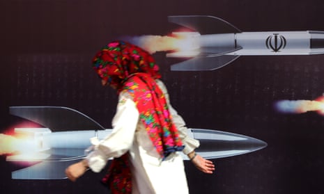 A person in Tehran passes a mural depicting missiles