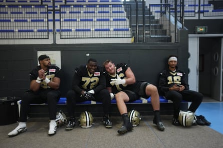 Saints players Fant, Richards, Edwards and Lance sit on a bench, helmets at their feet, posing for the camera