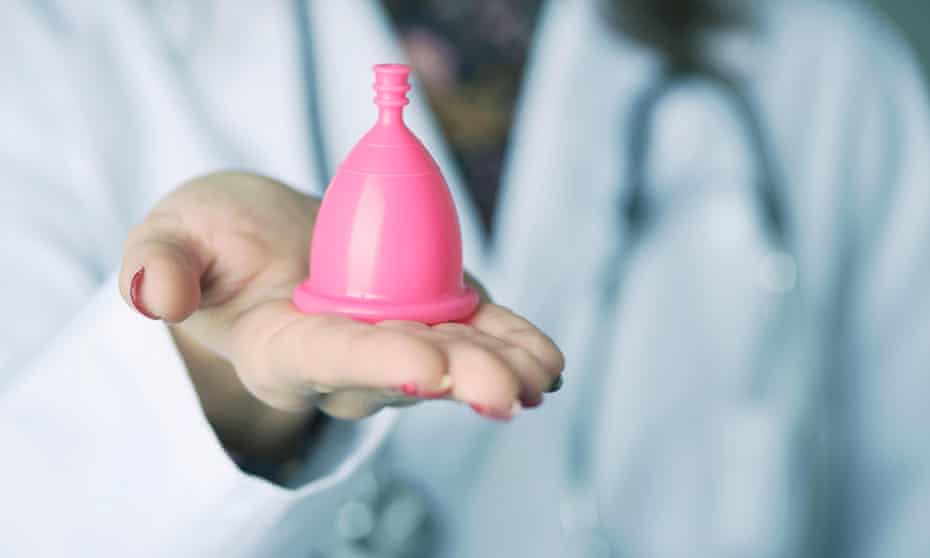 closeup of a young caucasian doctor woman with a pink menstrual cup in her hand