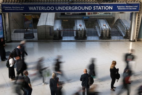 Travellers pause and walk past a closed London Underground entrance during the morning rush hour, as London tube strikes continue, at Waterloo Station in London.