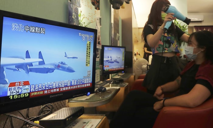 A customer watches a report on recent tensions between China and Taiwan at a beauty salon in Taipei.