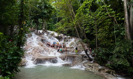 Tourists climbing the Dunns River falls in a lush tropical landscape. Ocho Rios, Jamaica.