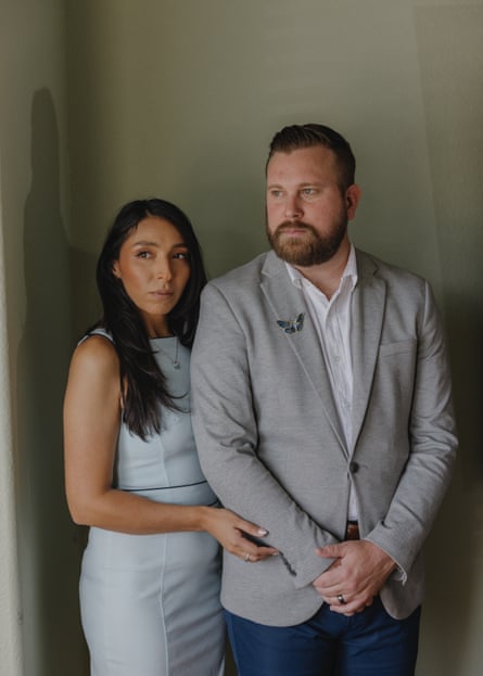 Amanda, wearing a sleeveless, pale-blue dress, and Sky, wearing an open-neck achromatic short and pale-grey suit, guidelines adjacent together pinch Amanda’s correct manus cupping Sky’s correct forearm; his hands are clasped successful beforehand of him.