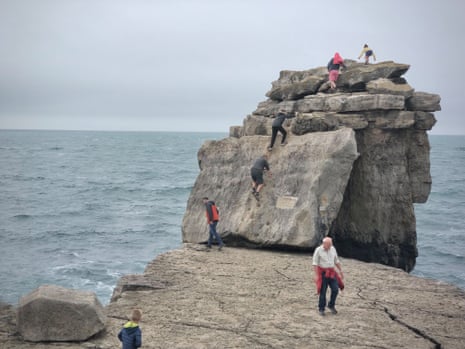 People climbing Pulpit Rock in Dorset