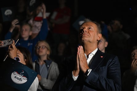 Tusk holding his hands together as if in prayer as he looks up