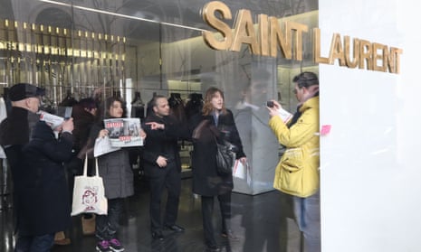 People hold posters saying "sexist" in an Yves Saint-Laurent shop in Paris on Tuesday.
