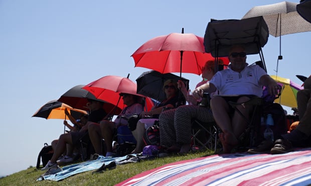 Spectators protect themselves from the sun before the British Formula One Grand Prix at the Silverstone