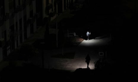Local residents light their way as they walk outside an apartment block in Kyiv amid power outages after Russian attacks