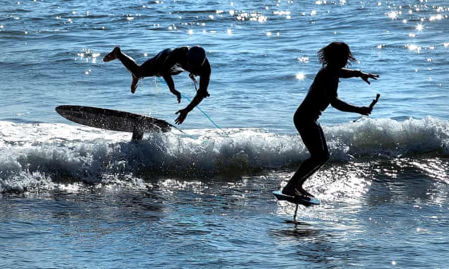 Matt Hamilton, left, takes a tumble as he and friend, Josh Lenny ride hydrofoil surfboards as Surfrider Beach in Malibu.