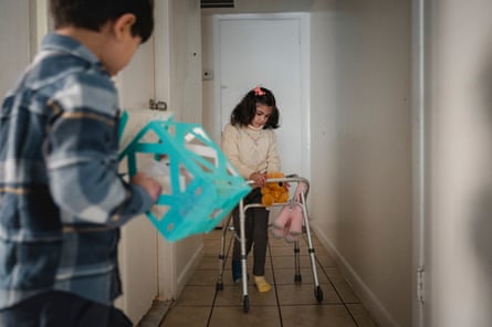 a girl with a walker and a boy carrying a box