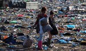 Festivalgoers leave the Glastonbury site through mounds of rubbish.