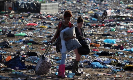 Festivalgoers leave the Glastonbury site through mounds of rubbish.