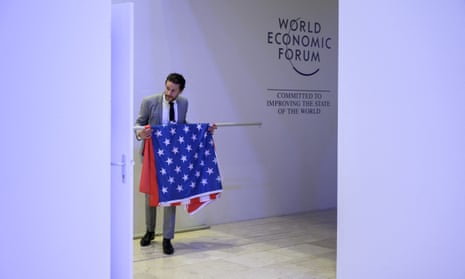 A World Economic Forum employee holds a US and a Chinese flag prior to a photo-op between the US and China special climate envoys.