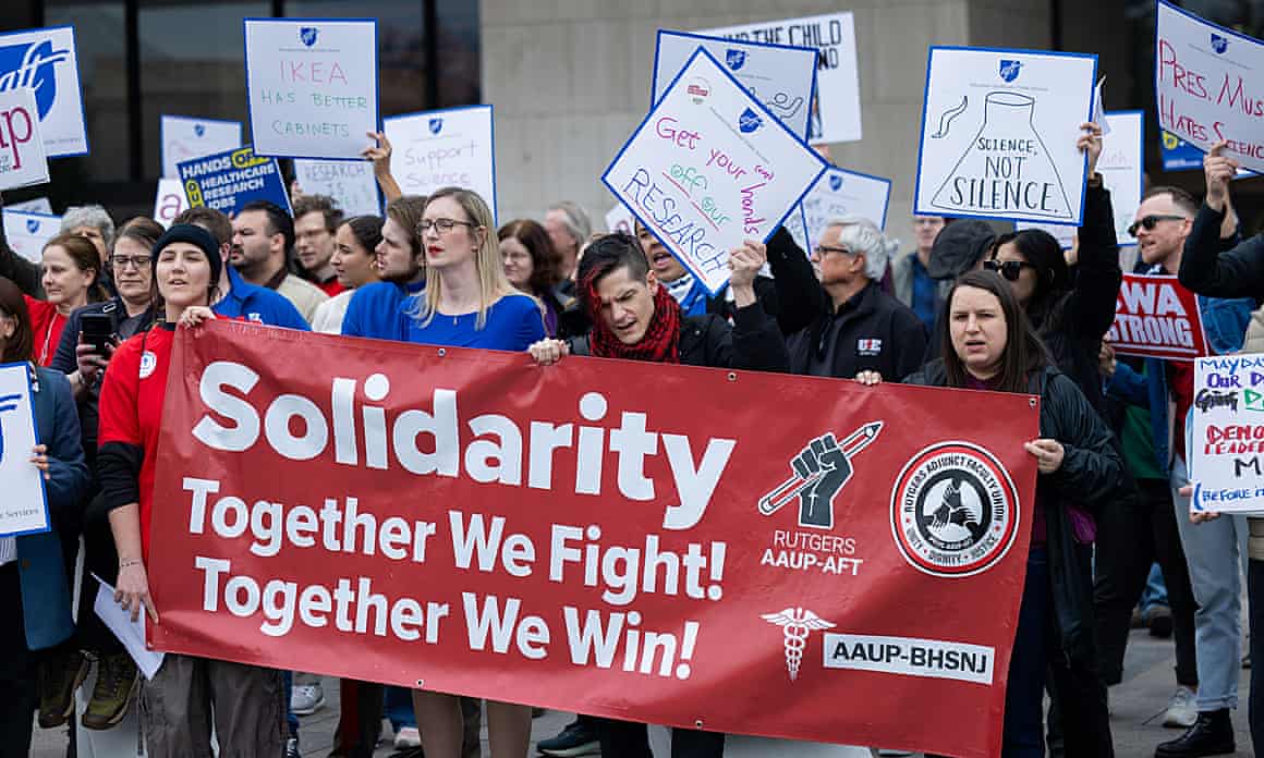 Protesters holding a sign reading 'Solidarity, together we fight, together we win'