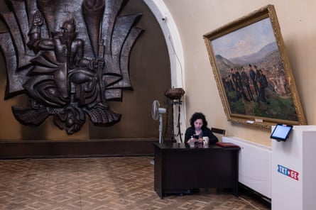 A woman takes a break at her desk outside the Stalin Museum, beneath a large framed painting