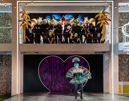 Samuel Boden dances in flamboyant dress as the rest of the cast looks down at him in Platée.