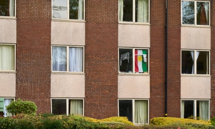 Exterior view of rows of windows, one of which has a flag hanging inside