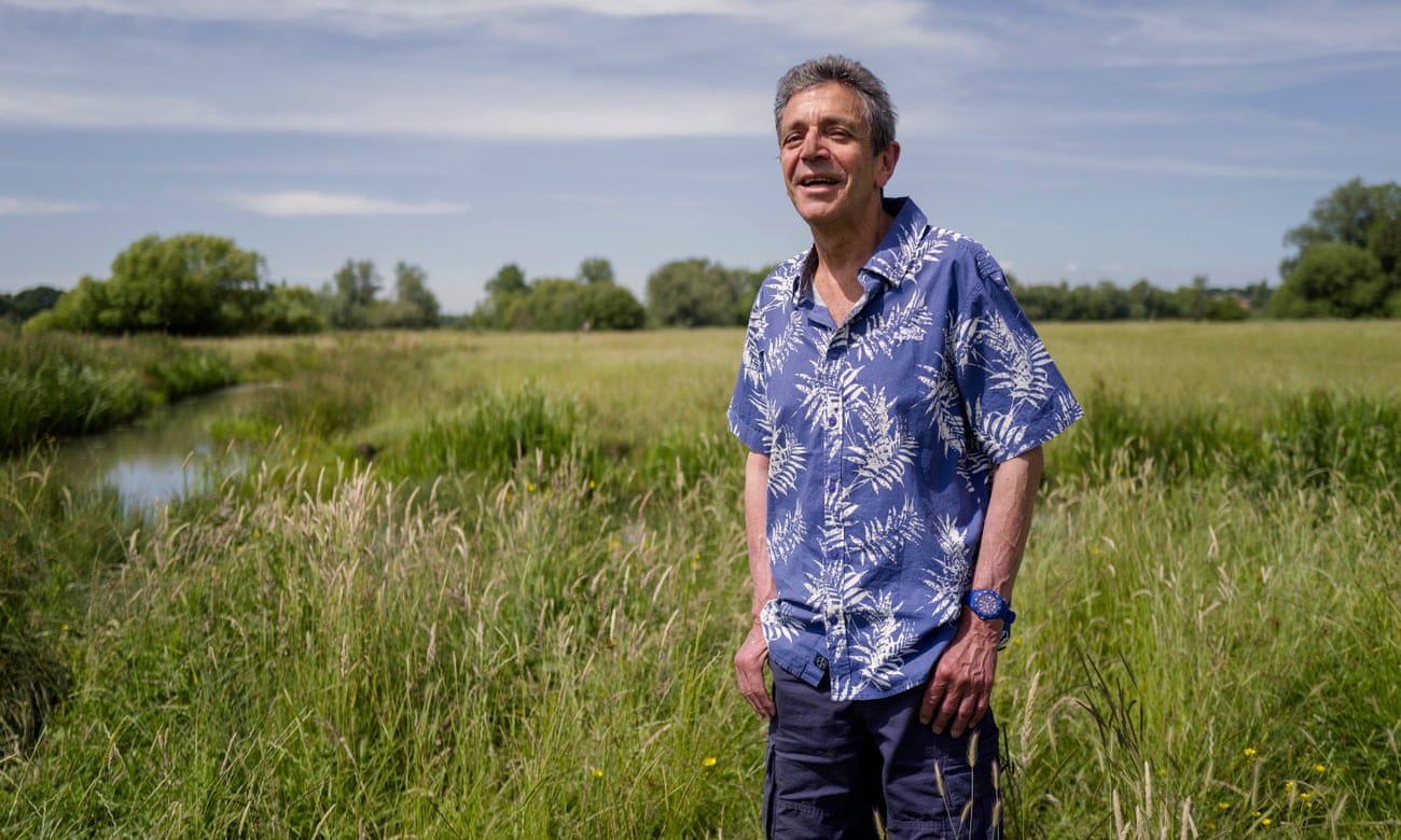 Writer Mike Nicholls, standing in a field near a stream, in  Suffolk.