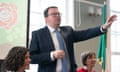 Conor McGinn speaking at the London Irish Centre: he is standing with one arm outstretched and wears a dark suit, white shirt, tie and glasses