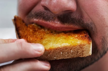 نمای نزدیک مردی که در حال خوردن نان تست است 