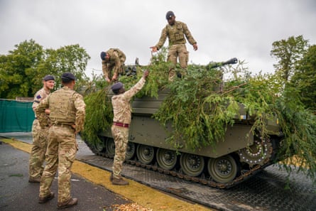 Soldiers look at and climb on armoured vehicle.