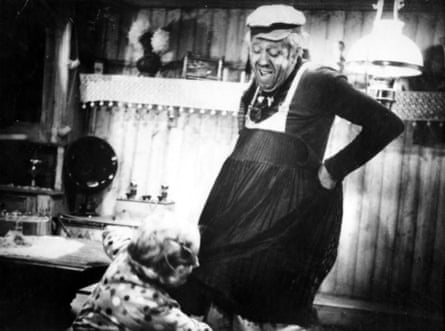 Black and white image of man in hat holding up skirt while woman pins the hem