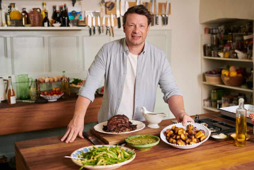 Jamie Oliver photographed in his kitchen with a selection of dishes on the table in front of him