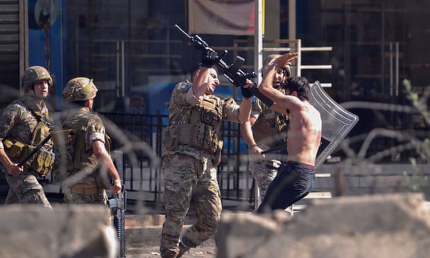 A soldier strikes a protester with his rifle