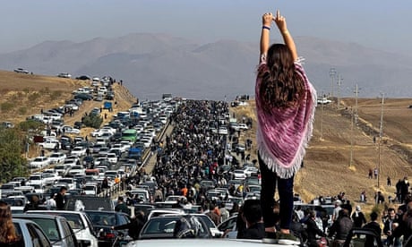This UGC image posted on Twitter reportedly on October 26, 2022 shows an unveiled woman standing on top of a vehicle as thousands make their way towards Aichi cemetery in Saqez, Mahsa Amini's home town in the western Iranian province of Kurdistan, to mark 40 days since her death, defying heightened security measures as part of a bloody crackdown on women-led protests. - A wave of unrest has rocked Iran since 22-year-old Amini died on September 16 following her arrest by the morality police in Tehran for allegedly breaching the country's strict rules on hijab headscarves and modest clothing. (Photo by UGC / AFP)