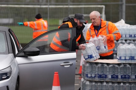 Workers hand over bottled water at a water station in East Grinstead
