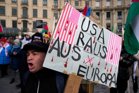 A man holds a poster reading: ‘USA: Out of Europe’ during a protest against the Munich Security Conference.