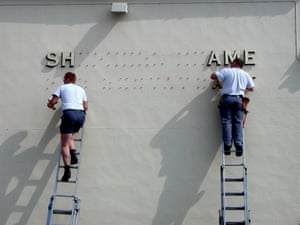 Two men on ladders leaning against a wall fix individual letters to create a sign on the facade of a building, Deal, Kent