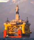 FILE - In this April 17, 2015 file photo, with the Olympic Mountains in the background, a small boat crosses in front of the Transocean Polar Pioneer, a semi-submersible drilling unit that Royal Dutch Shell leases from Transocean Ltd., as it arrives in Port Angeles, Wash., aboard a transport ship after traveling across the Pacific before its eventual Arctic destination. 