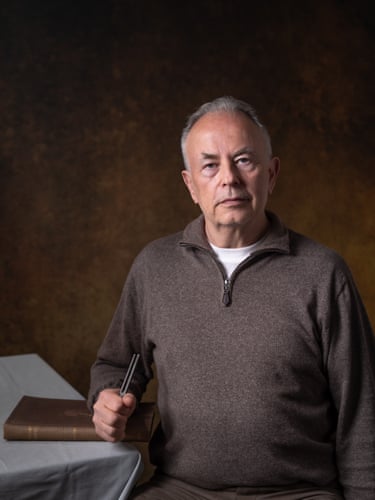 A man holds a tuning fork and rests his arm on a book