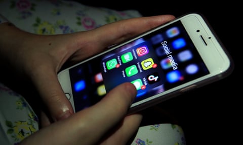 A child looks at social media apps on a mobile phone