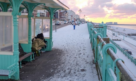 A homeless person tries to stay warm in a shelter on Brighton seafront in freezing conditions