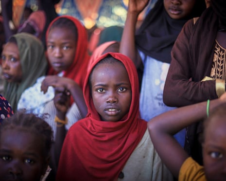 A girl looking straight at the camera in a crowd of women and children